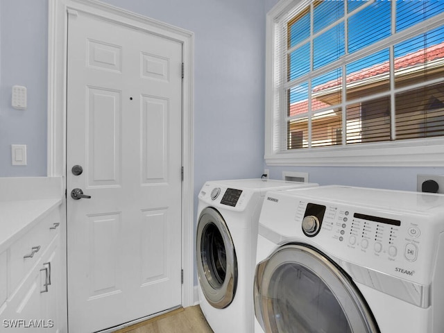 clothes washing area featuring light hardwood / wood-style floors, cabinets, and washing machine and clothes dryer