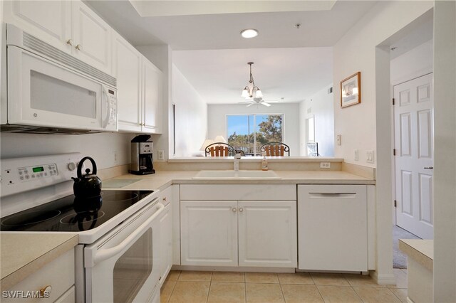 kitchen featuring white appliances, sink, light tile patterned floors, white cabinets, and hanging light fixtures