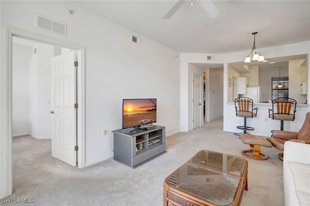 carpeted living room with ceiling fan with notable chandelier