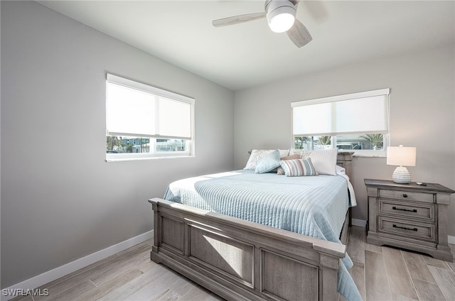 bedroom featuring light wood-type flooring, ceiling fan, and multiple windows