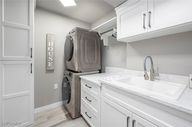 laundry area with sink, cabinets, stacked washer / dryer, and light wood-type flooring