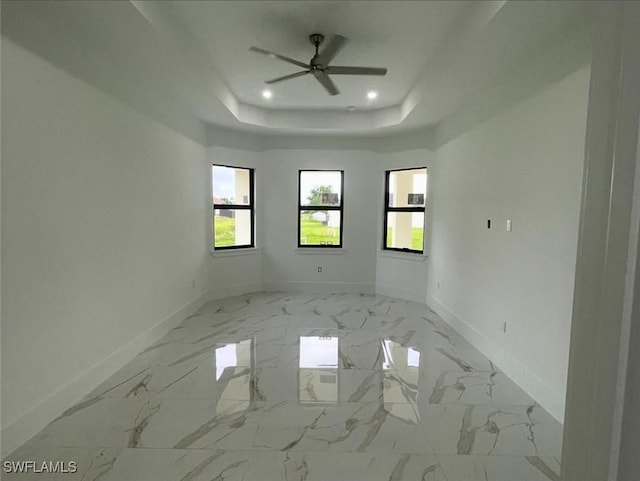 empty room featuring a tray ceiling and ceiling fan