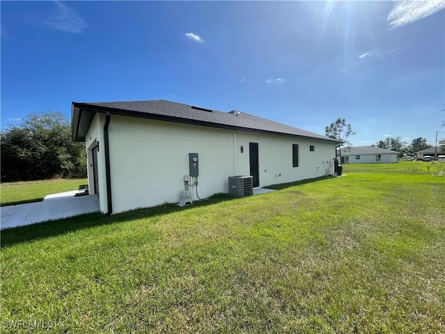 rear view of house with central air condition unit and a yard