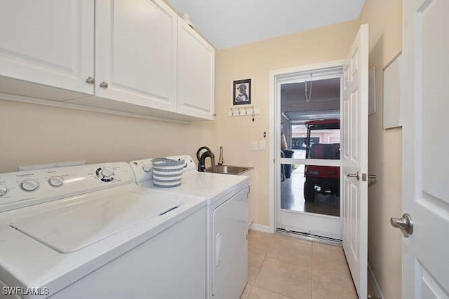 clothes washing area with washer and dryer, light tile patterned floors, sink, and cabinets