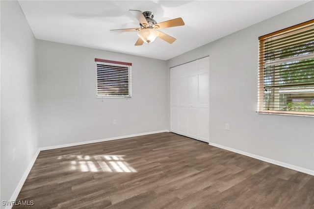 unfurnished bedroom featuring dark hardwood / wood-style floors, ceiling fan, and a closet