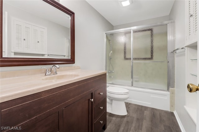 full bathroom with wood-type flooring, vanity, shower / bath combination with glass door, and toilet