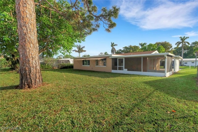 back of house featuring a yard and a sunroom