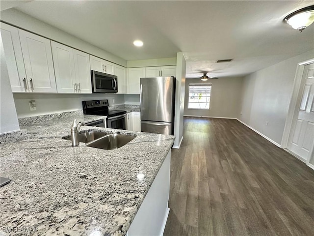 kitchen featuring sink, kitchen peninsula, appliances with stainless steel finishes, light stone counters, and white cabinetry