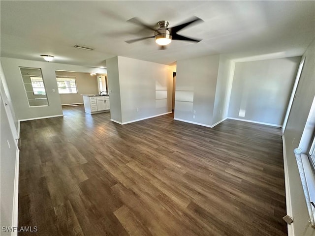 unfurnished living room featuring dark wood-type flooring and ceiling fan