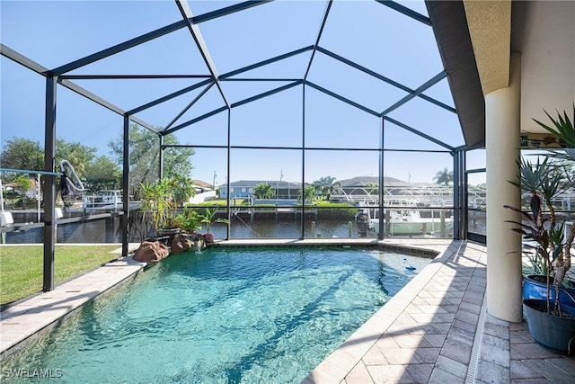 view of pool with glass enclosure, a water view, and a patio