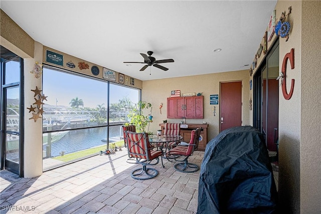 sunroom / solarium featuring a water view and ceiling fan