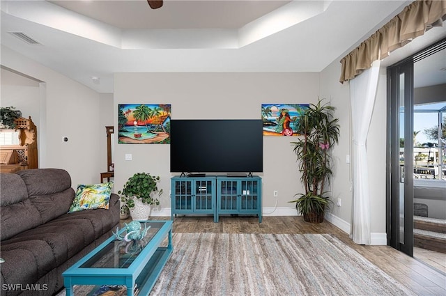 living room with hardwood / wood-style flooring and a raised ceiling