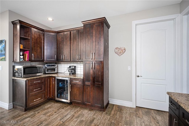 kitchen featuring light stone countertops, dark brown cabinets, dark hardwood / wood-style floors, and beverage cooler