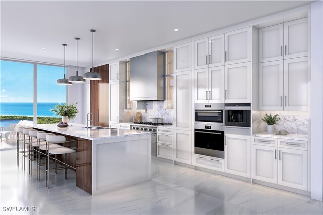 kitchen with decorative backsplash, a water view, a kitchen bar, and a kitchen island with sink