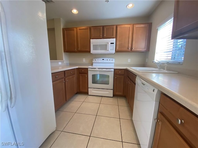 kitchen featuring sink, light tile patterned flooring, and white appliances