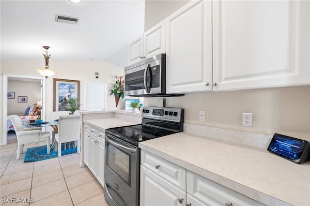 kitchen with light tile patterned floors, appliances with stainless steel finishes, hanging light fixtures, white cabinets, and vaulted ceiling