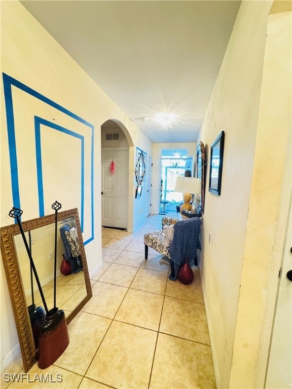 hall featuring light tile patterned floors and an inviting chandelier