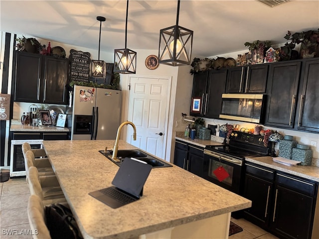 kitchen with sink, decorative light fixtures, a center island with sink, light tile patterned floors, and appliances with stainless steel finishes