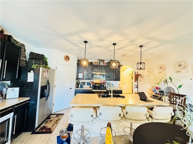 kitchen featuring stainless steel appliances, a kitchen breakfast bar, pendant lighting, a center island with sink, and light tile patterned flooring