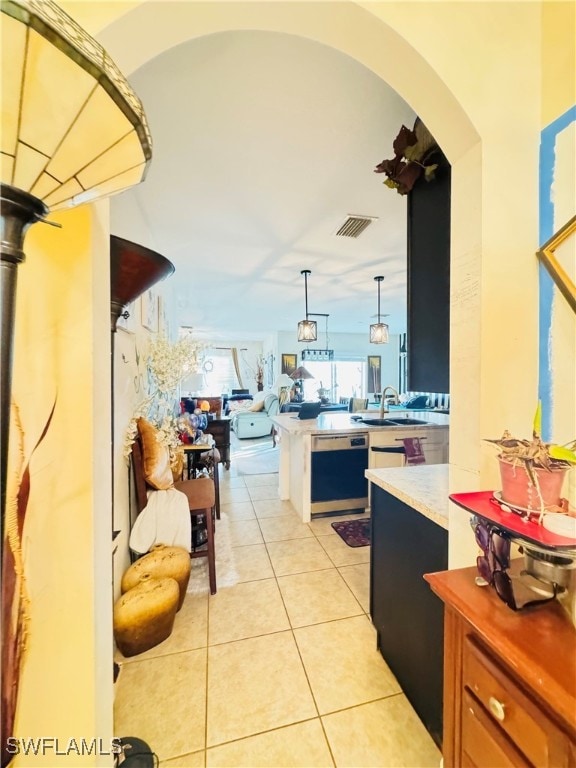 kitchen with dishwasher, light tile patterned floors, sink, and decorative light fixtures