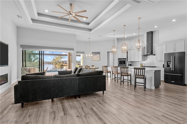 living room with ceiling fan, light hardwood / wood-style floors, and a high ceiling