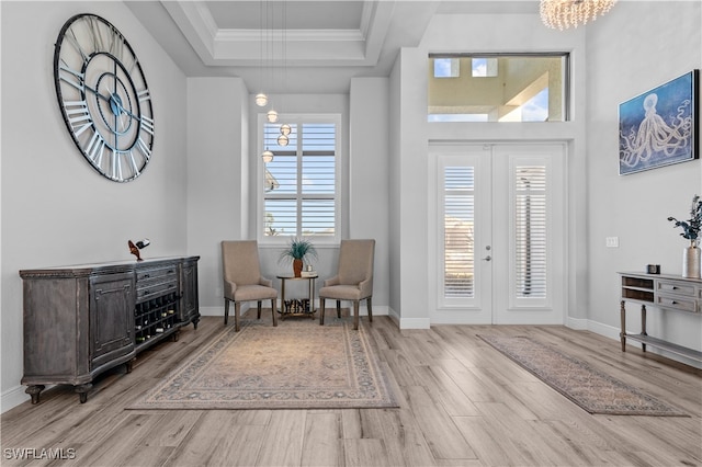 entryway featuring a tray ceiling, crown molding, light hardwood / wood-style flooring, and french doors