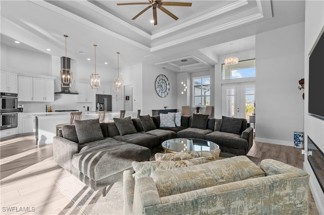 living room featuring crown molding, ceiling fan, light hardwood / wood-style floors, and a high ceiling