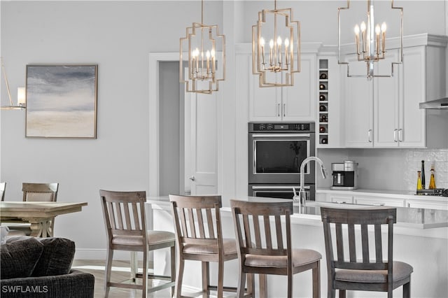 kitchen featuring white cabinetry, pendant lighting, decorative backsplash, a breakfast bar, and appliances with stainless steel finishes