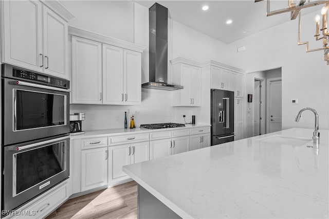 kitchen with white cabinetry, wall chimney range hood, and appliances with stainless steel finishes