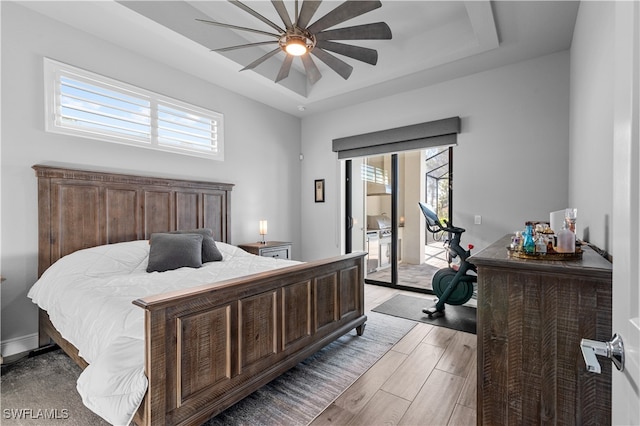 bedroom with a tray ceiling, multiple windows, ceiling fan, and light hardwood / wood-style floors