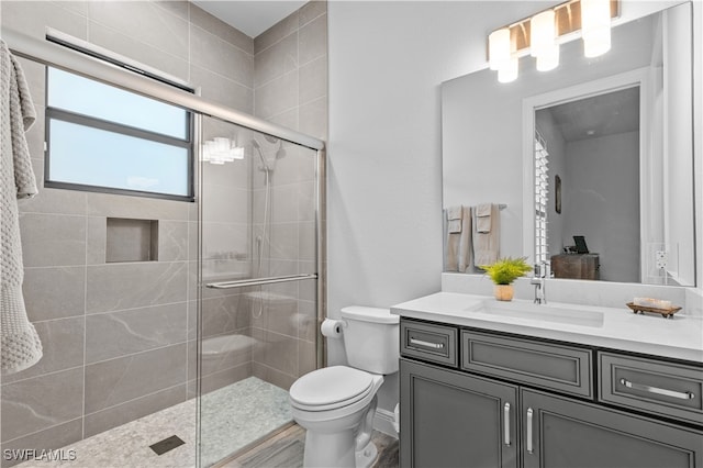 bathroom featuring hardwood / wood-style flooring, a shower with door, vanity, and toilet