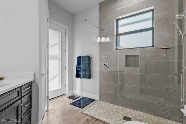 bathroom with hardwood / wood-style floors, vanity, and a tile shower