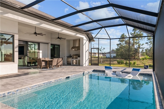 view of pool featuring area for grilling, ceiling fan, exterior kitchen, glass enclosure, and a patio