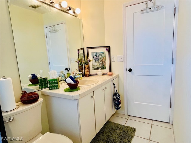 bathroom with toilet, vanity, and tile patterned flooring