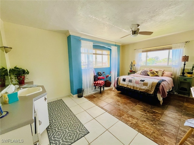 bedroom with a textured ceiling, ceiling fan, tile patterned flooring, and sink