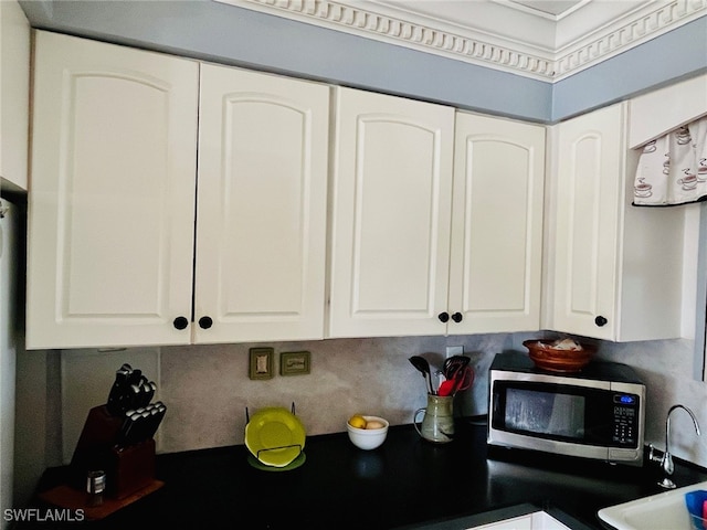 kitchen featuring white cabinetry, decorative backsplash, ornamental molding, and sink