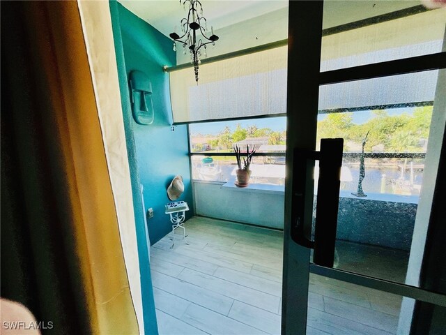 entryway with a water view, wood-type flooring, and an inviting chandelier