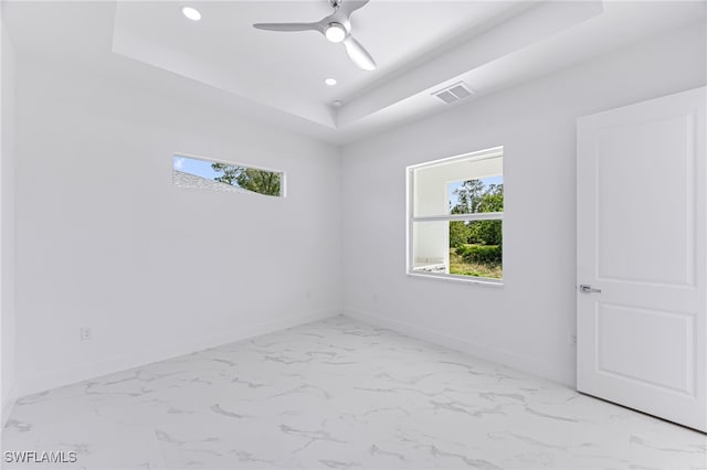 unfurnished room featuring ceiling fan and a raised ceiling