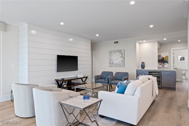 living room featuring bar area, light hardwood / wood-style floors, and beverage cooler