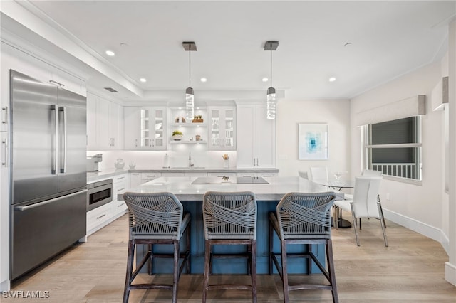 kitchen featuring white cabinetry, hanging light fixtures, light hardwood / wood-style flooring, built in appliances, and a kitchen island