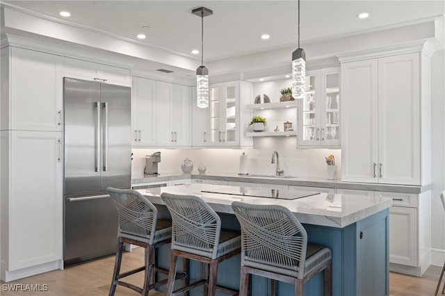 kitchen with white cabinetry, built in refrigerator, a breakfast bar, and a kitchen island