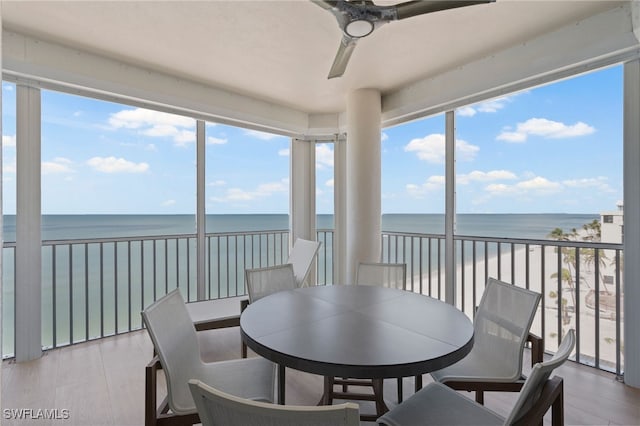 sunroom / solarium featuring a view of the beach, a water view, and plenty of natural light