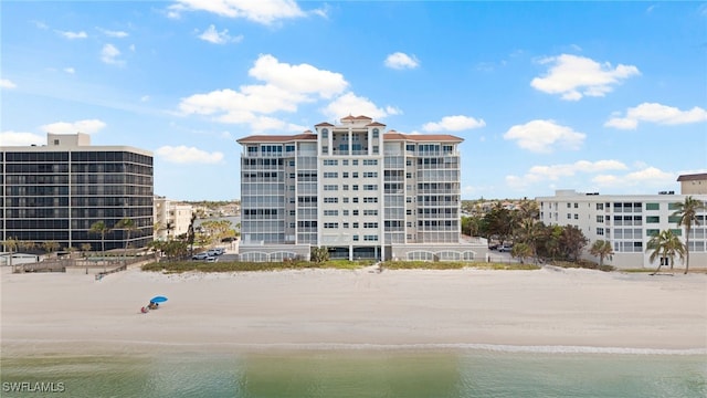 view of building exterior featuring a water view and a beach view