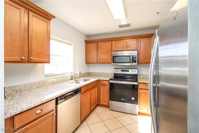 kitchen with light stone counters, sink, appliances with stainless steel finishes, and light tile patterned floors