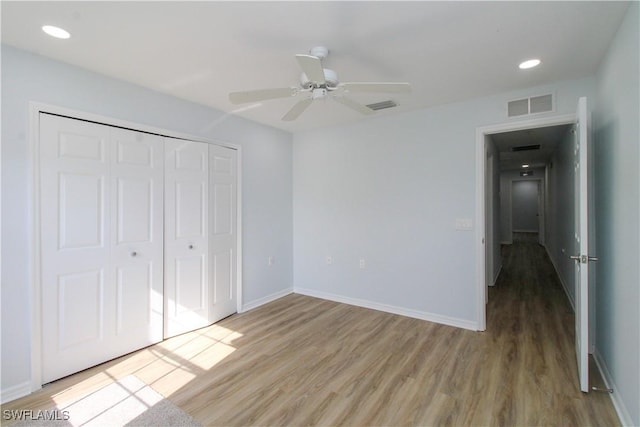 unfurnished bedroom featuring ceiling fan, a closet, and light wood-type flooring