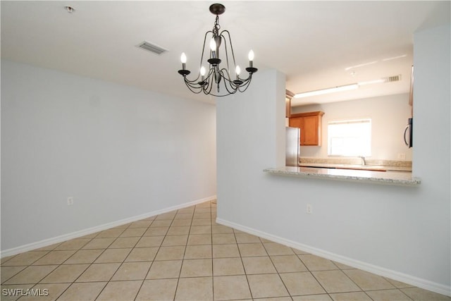 unfurnished room with a notable chandelier, light tile patterned floors, and sink