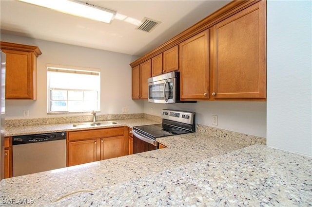 kitchen with sink, light stone countertops, and appliances with stainless steel finishes