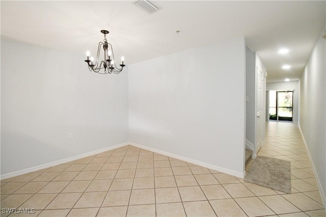 spare room featuring a chandelier and light tile patterned flooring