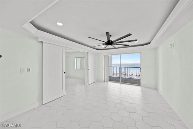 spare room featuring a tray ceiling, ceiling fan, and a water view