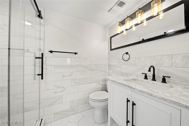 bathroom with vanity, tile patterned floors, toilet, tile walls, and walk in shower